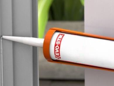 Applying sealant along a window or door frame joint with a sealant gun to create a durable weatherproof seal.
