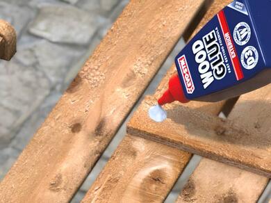 Applying wood glue to a wooden furniture joint before repairing and restoring damaged wood.