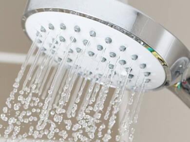 Water flowing from a shower head, highlighting the importance of maintaining a watertight seal in a shower enclosure.