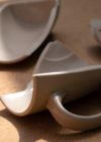 Broken ceramic mug pieces on a wooden surface